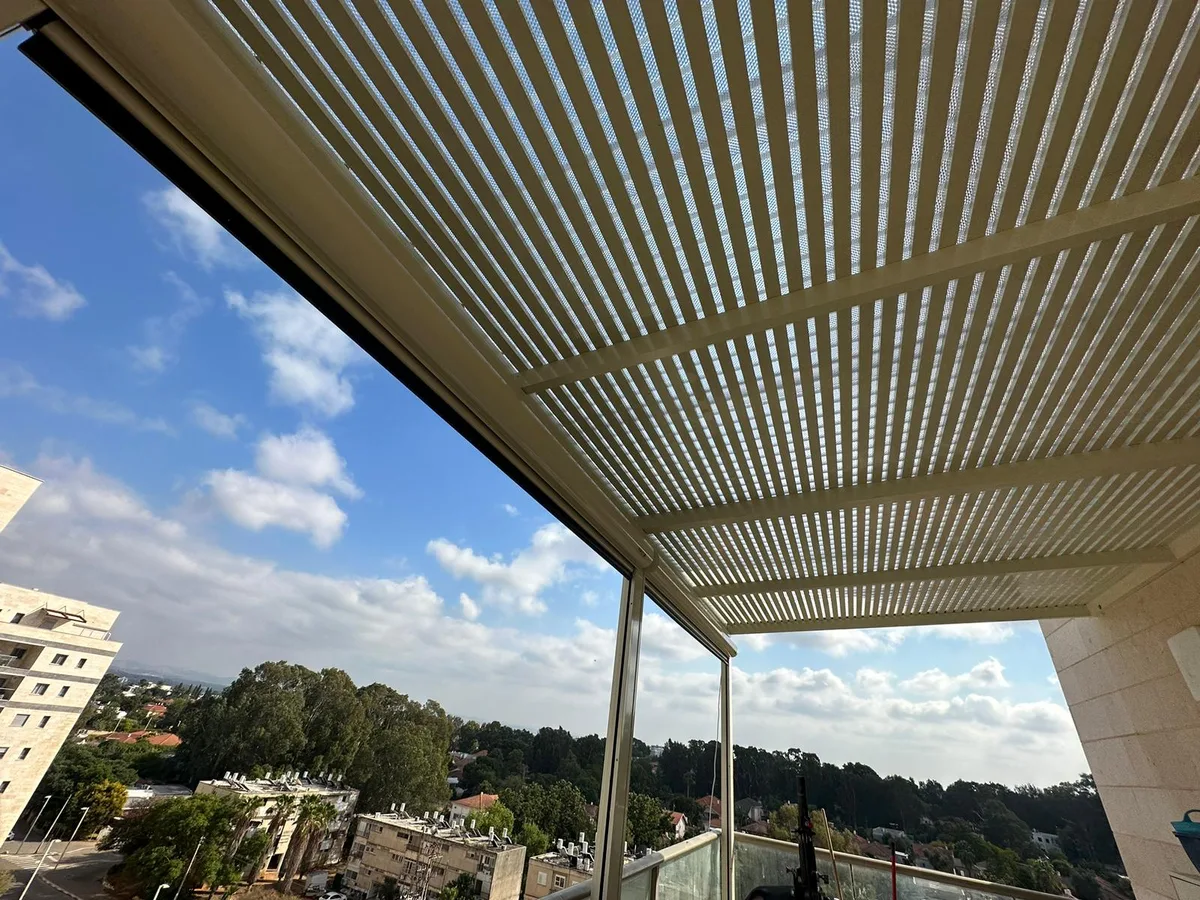 פרגולת אלומיניום כהה מעל מרפסת עם נוף פתוח
